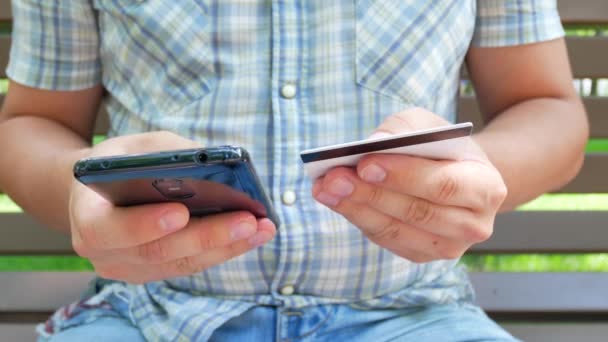Мужские руки с черным смартфоном и дебетовой или кредитной картой — стоковое видео