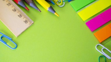 Okul üzerinde yeşil arka plan sağlar. Kalem, kurşun kalem, makas, cetvel, ataç ve bir işaretleyici masanın üzerinde. Yukarıdan kopya alanı ile göster