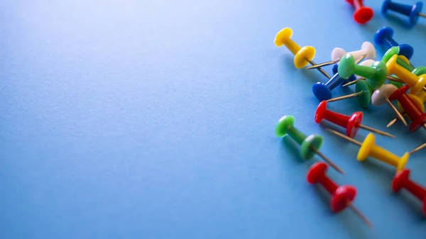 Color push pins on blue background for copyspace. Concept of office administrator business, financial inspector or secretary. View from above with copy space