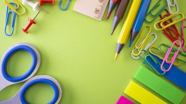 Okul üzerinde yeşil arka plan sağlar. Kalem, kurşun kalem, makas, cetvel, ataç ve bir işaretleyici masanın üzerinde. Yukarıdan kopya alanı ile göster