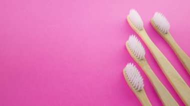 Pembe bir arka plan üzerinde beyaz tahta diş fırçaları
