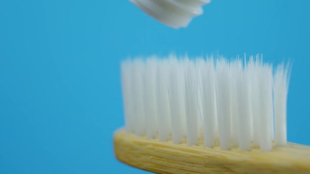 Tandkräm som pressas från röret in i vit trä borste — Stockvideo