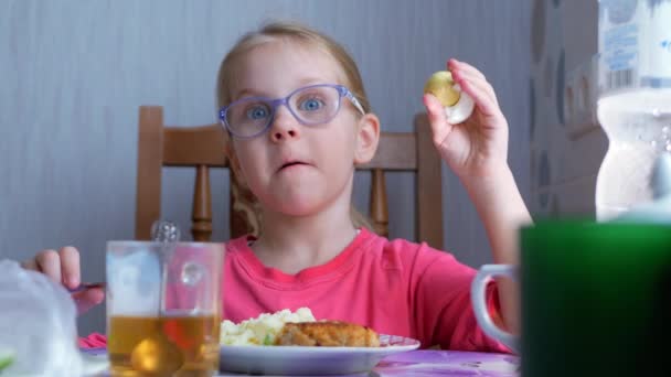 Pequena menina bonita comendo um ovo cozido na mesa na cozinha — Vídeo de Stock