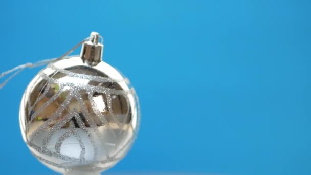 Bolas de Navidad decoradas de plata girando sobre fondo azul — Vídeos de Stock