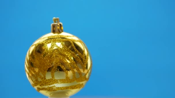 Bolas de Navidad amarillas decoradas girando sobre fondo azul — Vídeos de Stock