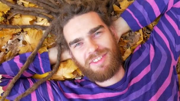 Χαμογελαστός άνθρωπος ξαπλωμένος σε πεσμένα φύλλα το φθινόπωρο πάρκο — Αρχείο Βίντεο