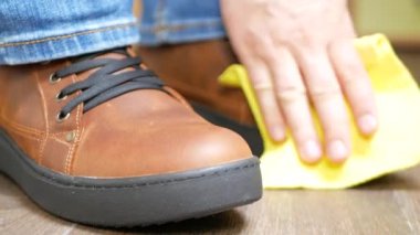 Kahverengi deri ayakkabı ile sarı bir bez toz el