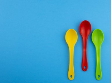 Sarı kırmızı yeşil plastik kaşık boşaltmak mavi zemin üzerine metin için