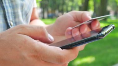 Adam siyah smartphone ve banka veya kredi kartı tutan eller