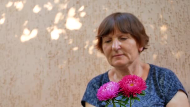 Пожилая женщина флорист делает букет с Михайловской маргаритки или астер — стоковое видео