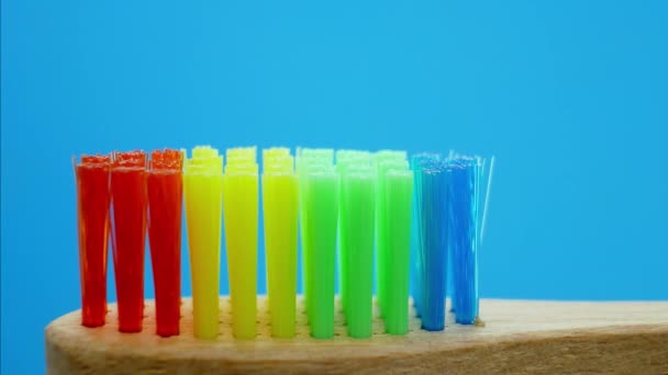 Tandpasta geperst uit buis in regenboog houten borstel — Stockvideo