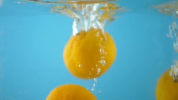 Naranja frutas cayendo en el agua y salpicaduras — Vídeo de stock