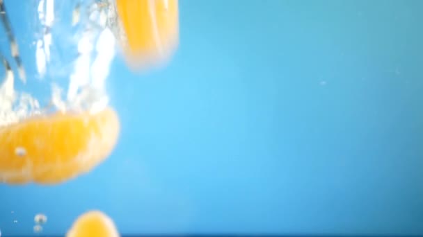 亮的五颜六色的橘子多汁的水果片, 叫橘子、柑橘或克莱门汀, 带着气泡掉进水里 — 图库视频影像
