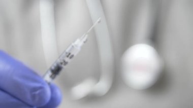 Doktor phonendoscope ve mavi eldivenli bir aşı şırıngayla sunar