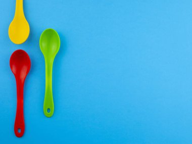 Sarı kırmızı yeşil plastik kaşık boşaltmak mavi zemin üzerine metin için