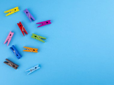 Renkli ahşap clothespins mandal bir mavi arka plan ve metin için boş alan