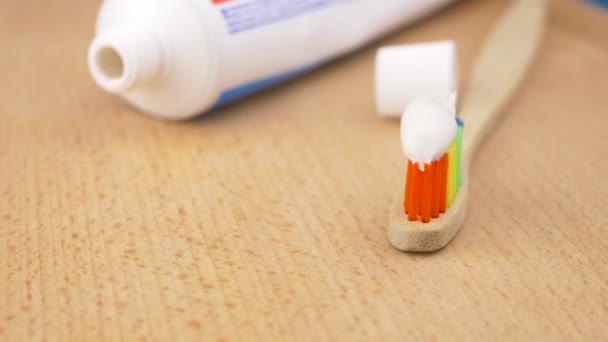 Cepillo de dientes con pasta de dientes sobre fondo de madera — Vídeos de Stock