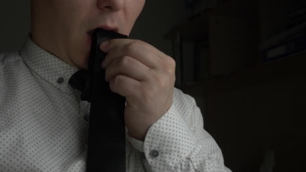 Менеджер или бизнесмен ест галстук в темном офисе — стоковое видео