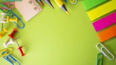 İleti örneği arka planı yeşil üzerinde. Kalem, kurşun kalem, makas, ataç, renkli itme pins ve masanın üzerinde. Yukarıdan kopya alanı ile göster