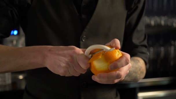 Barman cutting orange peel for fresh alcoholic drink — Stock Video