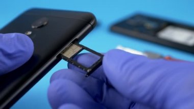 Mavi eldiven elinde siyah akıllı telefon Sim kartı yükler