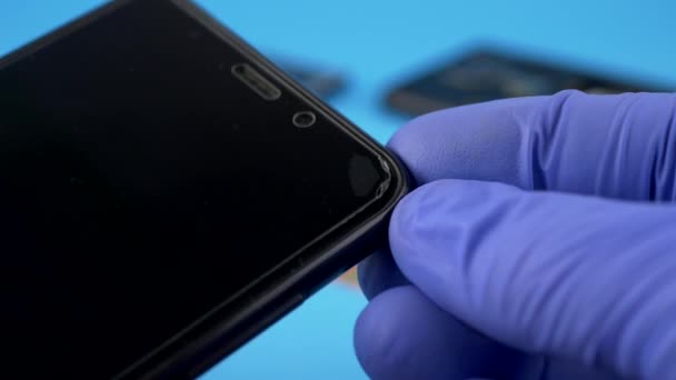 Технический работник держит поцарапанный черный смартфон — стоковое видео