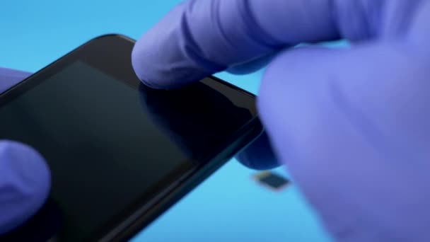 Technicus werknemer in blauw handschoenen houden zwarte smartphone — Stockvideo