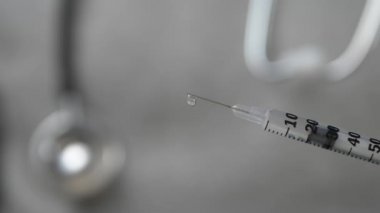 Doktor phonendoscope ve mavi eldivenli bir aşı şırıngayla sunar