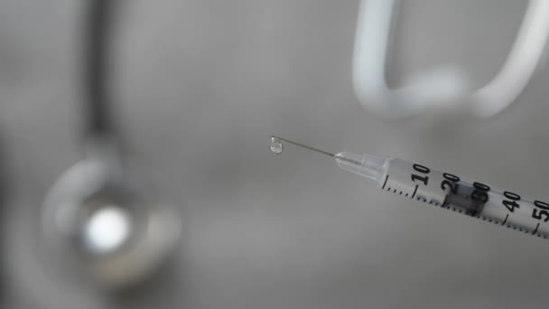 Il medico con fonendoscopio e guanti blu offre una siringa con un vaccino — Video Stock