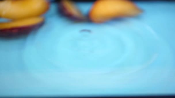 Slices of ripe plum splashing into the water — Stock Video