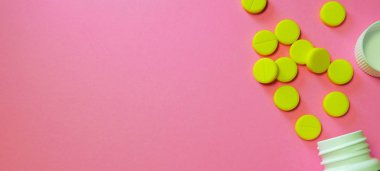 Sarı haplar ve kopya alanı pembe bir arka plan üzerinde beyaz şişe