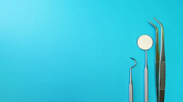 Herramientas dentales en consultorio dental: explorador dental, sonda de hoz, espejo dental. Higiene dental y salud imagen conceptual sobre superficie azul-verde para texto de copyspace —  Fotos de Stock