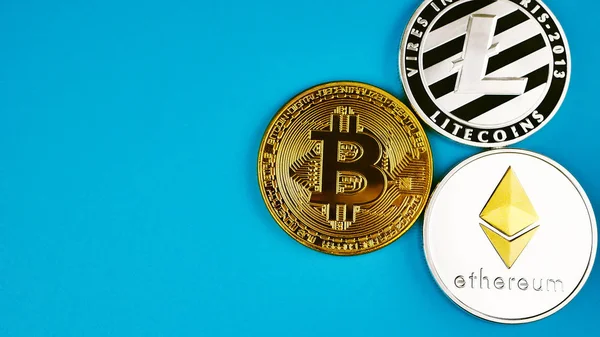 Virtueel geld Bitcoin, Litecoin en Ethereum munten op blauwe achtergrond voor copyspace tekst Rechtenvrije Stockfoto's
