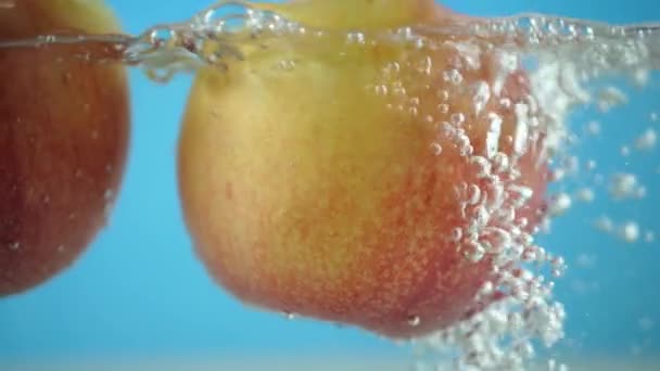 Manzana roja amarilla bajo el agua con un rastro de burbujas transparentes — Vídeos de Stock