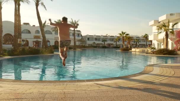 Frau in farbenfroher Badebekleidung springt in Schwimmbad — Stockvideo