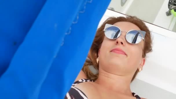 Ganska vacker flicka med ljusbrunt hår ligger på yacht och sola — Stockvideo