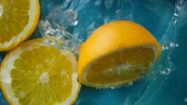 Нарезанные оранжевые погружения и брызги в воду — стоковое видео
