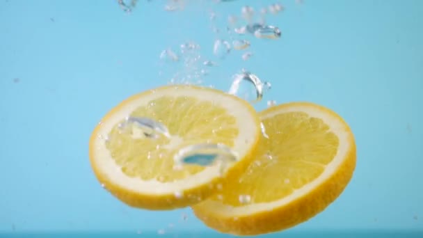 Naranja fresca en rodajas cayendo en el agua con salpicadura — Vídeos de Stock