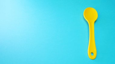 Mavi arka planda izole sarı plastik kaşık