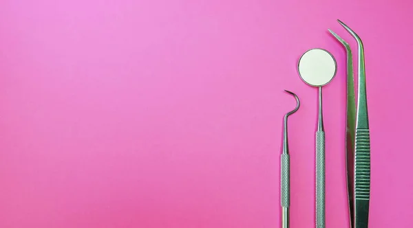 Herramientas para examinar, manipular, tratar, restaurar y eliminar los dientes y las estructuras orales circundantes en el fondo rosa. Instrumentos dentales para profesionales utilizados para proporcionar tratamiento dental —  Fotos de Stock