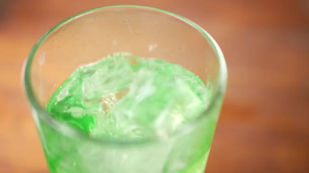Cubos de hielo cayendo en agua verde espumosa — Vídeos de Stock