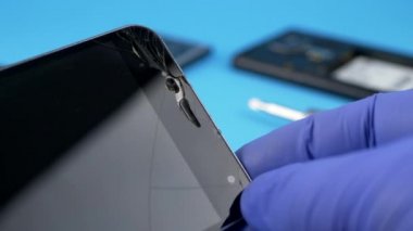 Teknisyen alt tutarak siyah smartphone çizik