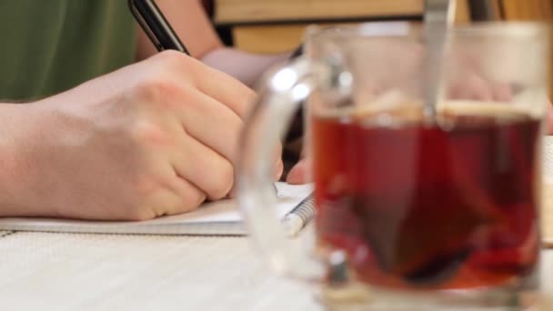 Студентський чоловік читає книгу та пише інформацію в блокноті — стокове відео