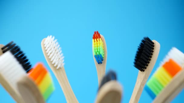 Escovas de dentes coloridas está girando em fundo azul — Vídeo de Stock