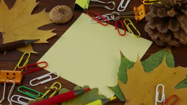 Hoja amarilla de papel con hojas de arce caído amarillo y suministros de oficina — Vídeo de stock