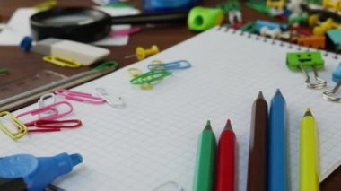 Kahverengi ahşap masa üzerinde çok renkli kalemler, kağıt klipler ve Notebook