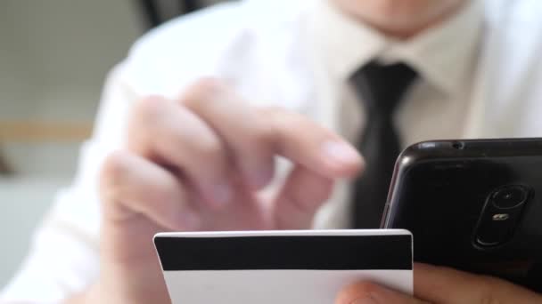 Чоловік тримає кредитну картку і використовує смартфон — стокове відео