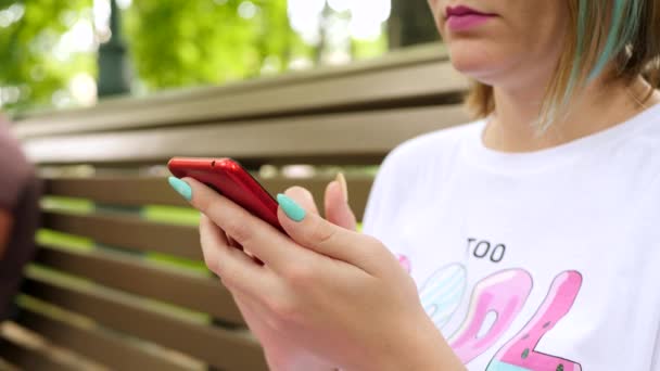 Femme utilisation Smartphone est assis sur le banc dans le parc d'été — Video