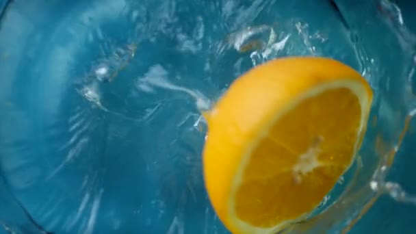 Gesneden oranje spatten in water — Stockvideo