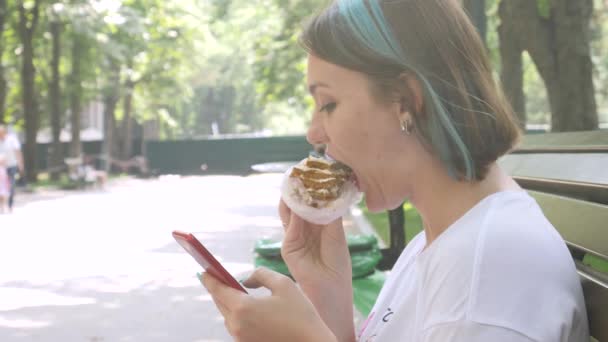 Charmante vrouw leest bericht op smartphone en eten cake — Stockvideo
